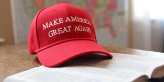 A red baseball cap with "Make America Great Again" sits on an open-faced Bible.