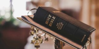 A thick bible sitting closed on a metal lectern in a church
