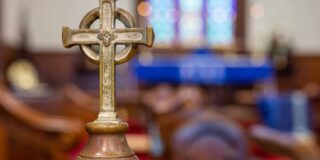 A close-up photo of a metal cross decoration that serves as the handle for an antique baptismal font at St. Luke's Episcopal Church in Cleveland, TN