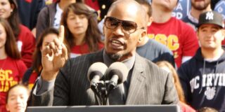 Actor Jaime Foxx stands speaking at an outdoor podium.