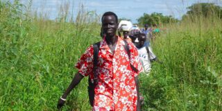 A line of Sudanese people are shown walking toward the camera.