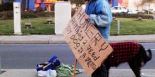 Homeless man with a dog and holding a sign asking for food