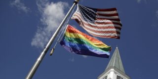 Church Steeple and flag pole with both the American flag and the Pride flag.