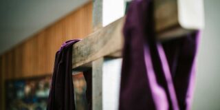 A wooden cross draped with a purple fabric and in a forced perspective.