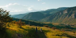 Two people walking surrounded by low mountains.