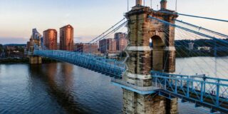 A large stone bridge over a river in Ohio with a city in the background.