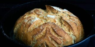 A loaf of fresh baked bread with decorative scoring.