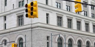 A stone U.S. Post Office building as seen from a street corner.