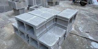 grey cinderblocks stacked in front of a partially completed wall.