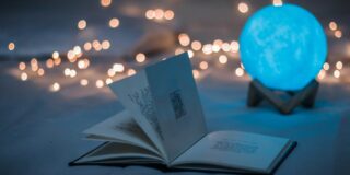 A magical looking scene with a book, fairy lights, and an illuminated ball.